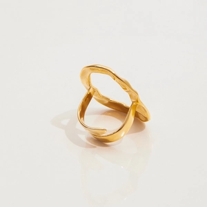 Vue détaillée d'une bague dorée ondulée en acier inoxydable sur une surface réfléchissante