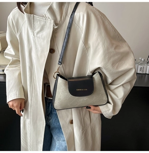 Close-up of contrast crossbody bag with black flap and matte grey body on a model