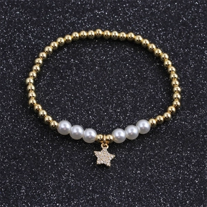 Detail of beaded bracelet featuring gold beads, white pearls and a star-shaped charm