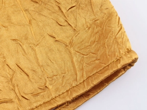 Detail van gouden satijnen stof met elegante plooien en fijne stikselafwerking