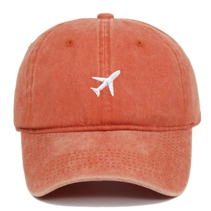 Detail of vintage orange cotton baseball cap with white airplane embroidery on the front