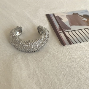 Detailed view of silver wide-band cuff bracelet with irregular wrinkled lava texture