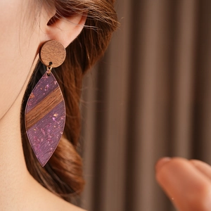 Gros plan de boucles d'oreilles minimalistes en bois et résine violette sur un mannequin