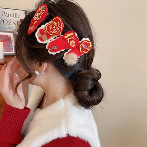 Detail of red Chinese New Year hair clips with embroidery on a person's hair