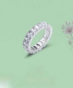Detail of S925 sterling silver eternity ring with oval cut diamonds on green floral background