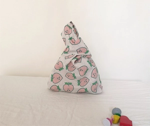 Detail of linen wrist bag featuring a peach print and unique twisted knot handle