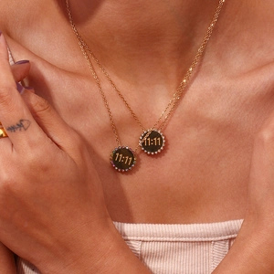 Close-up of gold disc pendants featuring 11:11 engraving and colorful zircon stones on model