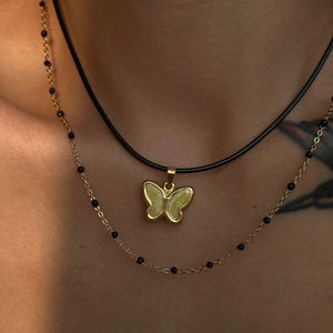 Close-up of vintage 18k gold plated butterfly pendant on black cord and beaded chain necklace