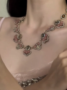 Close-up of vintage flower pendant necklace with pink resin petals and crystal accents