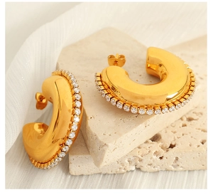 Detailed shot of golden C-shaped hoop earrings with sparkling zircon stones and metal backings