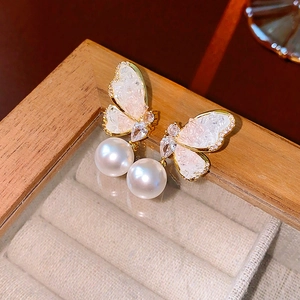 Close-up of butterfly earrings with pearls and pavé zircons in a vintage jewelry box