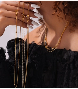 Detail view of multi-style layered gold plated necklaces with ball and box chain link textures