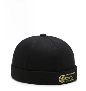 Detail of black cotton brimless cap with yellow embroidery and textured twill fabric