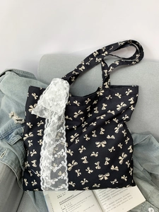 Detail of black canvas tote featuring white bow print and delicate floral lace trim