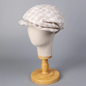 Macro detail of beige plaid cotton linen beret showing textured fabric and short brim