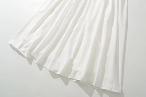 Detailed view of the white pleated hemline showcasing the flowing fabric texture
