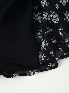 Makro-Detail des schwarzen Chiffonstoffs mit floralem Print, Lagenstruktur und Saumnaht