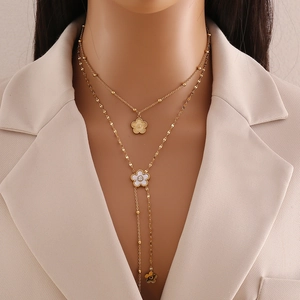 Detailed close-up of double-layered gold floral necklace with white enamel petals