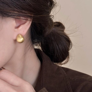 Detail of 18k gold plated brushed metal teardrop stud earring on a model ear