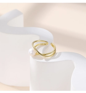 Detail of a minimalist gold crisscross ring featuring a round white pearl on top