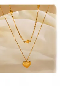 Gros plan détaillé d'un collier double couche à pendentif cœur doré sur soie