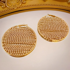 Macro shot of large gold hoop earrings with sparkling cubic zirconia crystals and mirror reflect