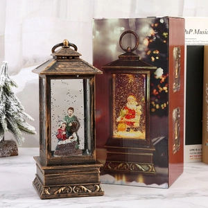 Detail view of bronze Christmas snow globe lantern alongside its festive gift packaging box