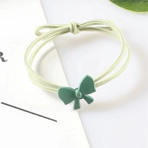 Detail of multi-strand green elastic hair tie with a matte resin bow decoration