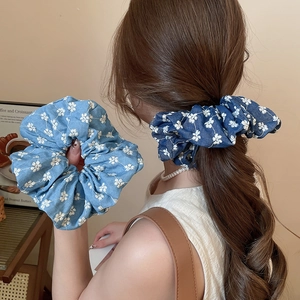 Detailed texture of blue floral scrunchies made of denim fabric with white flower prints