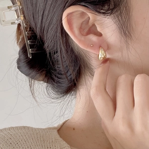 Detail of golden teardrop earring with zircons worn for a minimalist and elegant look