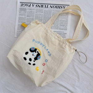 Close-up of cute puppy embroidery on a cream canvas tote bag with soft lighting