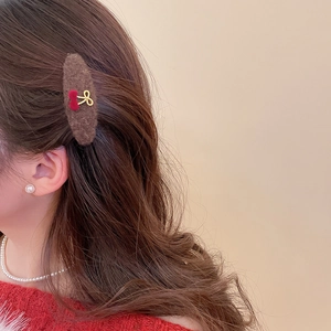 Retro plush brown hair clip with red cherry and gold bow detail worn on side hair