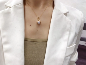 Detail of elegant gold necklace with purple pearl pendant and zircon accents on model