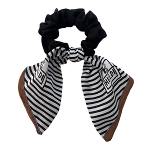 Elegant black and white striped scrunchie hair tie with brown edges on a white background