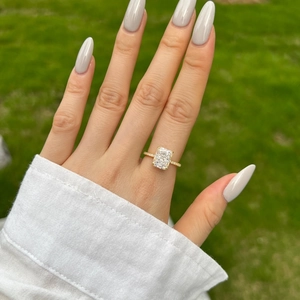 Detail of a rectangular ice-cut zircon ring in gold finish worn on finger outdoors