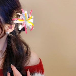 Detailed view of glowing plush firework hair clip worn on model with LED light effect