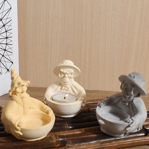 Three gothic skull candle holders in beige, yellow, and grey on a dark bamboo mat decor