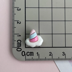 Mini pink resin unicorn horn with white cloud base measured on a scale mat for DIY deco
