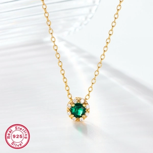 Macro view of 925 sterling silver gold necklace with a round green gemstone pendant