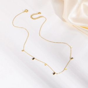 Macro shot of gold-plated titanium necklace with black rectangular charms on white silk