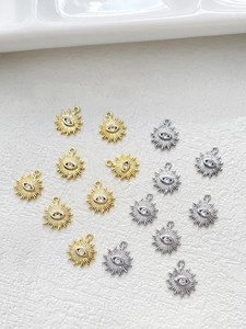 Detailed view of 14k gold and silver evil eye sunray charms with cubic zirconia