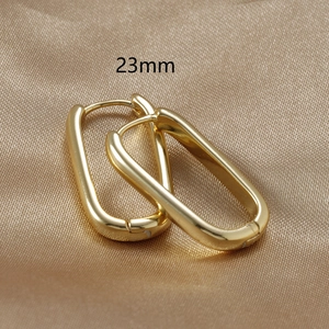 Close-up of 23mm gold-plated U-shaped minimalist hoop earrings on champagne silk fabric