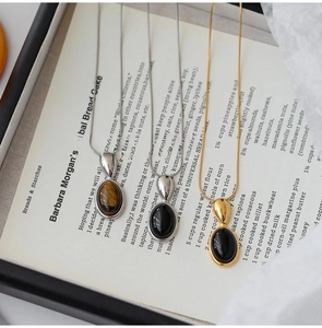 Close-up of resin oval pendant necklaces on book page showing gold and silver finishes