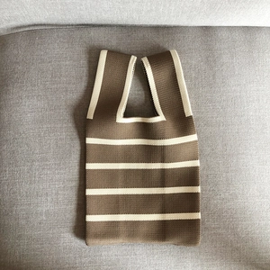 Detailed close-up of brown and beige striped knit tote bag on a grey fabric sofa