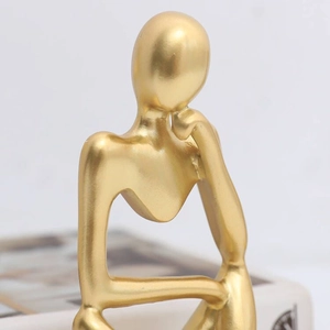 Close-up of a modern abstract thinker sculpture in matte gold finish for home decor