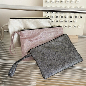 Glitter sequin cosmetic bags in silver, pink, and black with wristlets on display