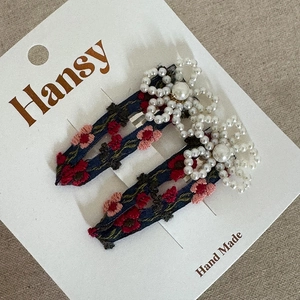 Detail of handmade navy fabric hair clips with floral embroidery and white pearl beads