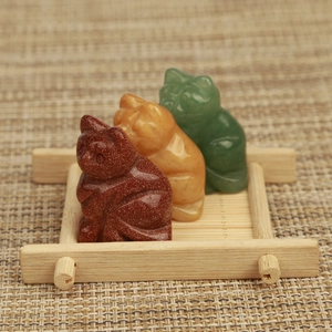 Three carved crystal cat figurines on a small wooden tray made of natural stones