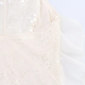 Détail de la broderie à paillettes ivoire et volants en tulle sur la robe courte