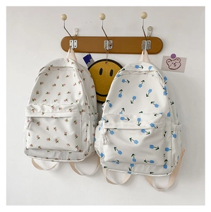 Detail of floral canvas backpacks featuring pink blossom and blue tulip prints on white fabric